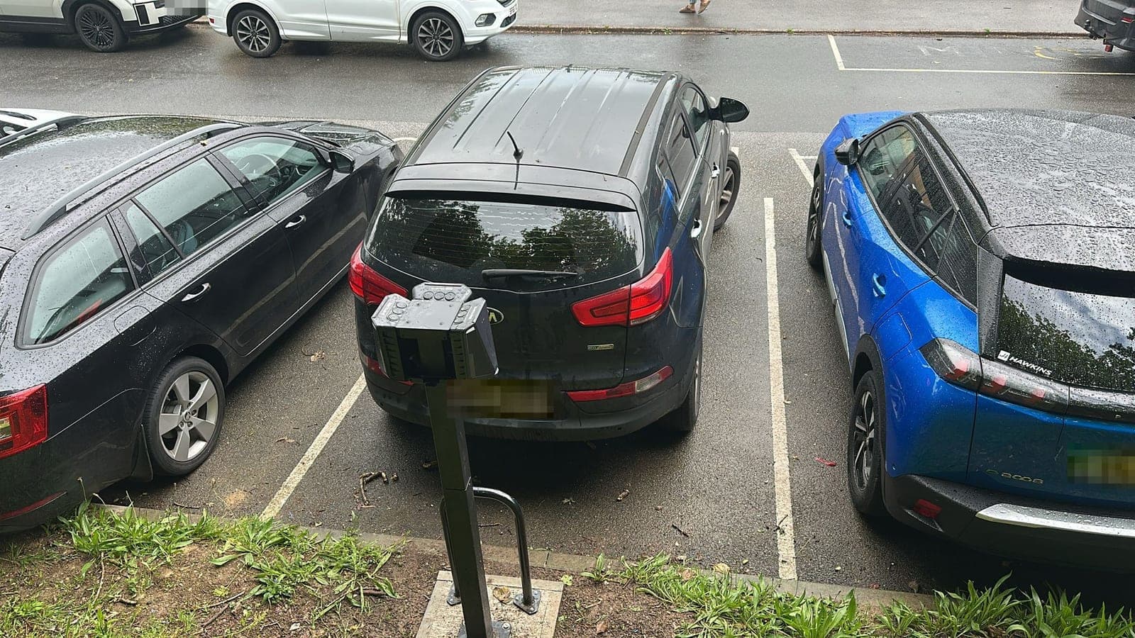 A twin-socket EV charger between two staff parking bays