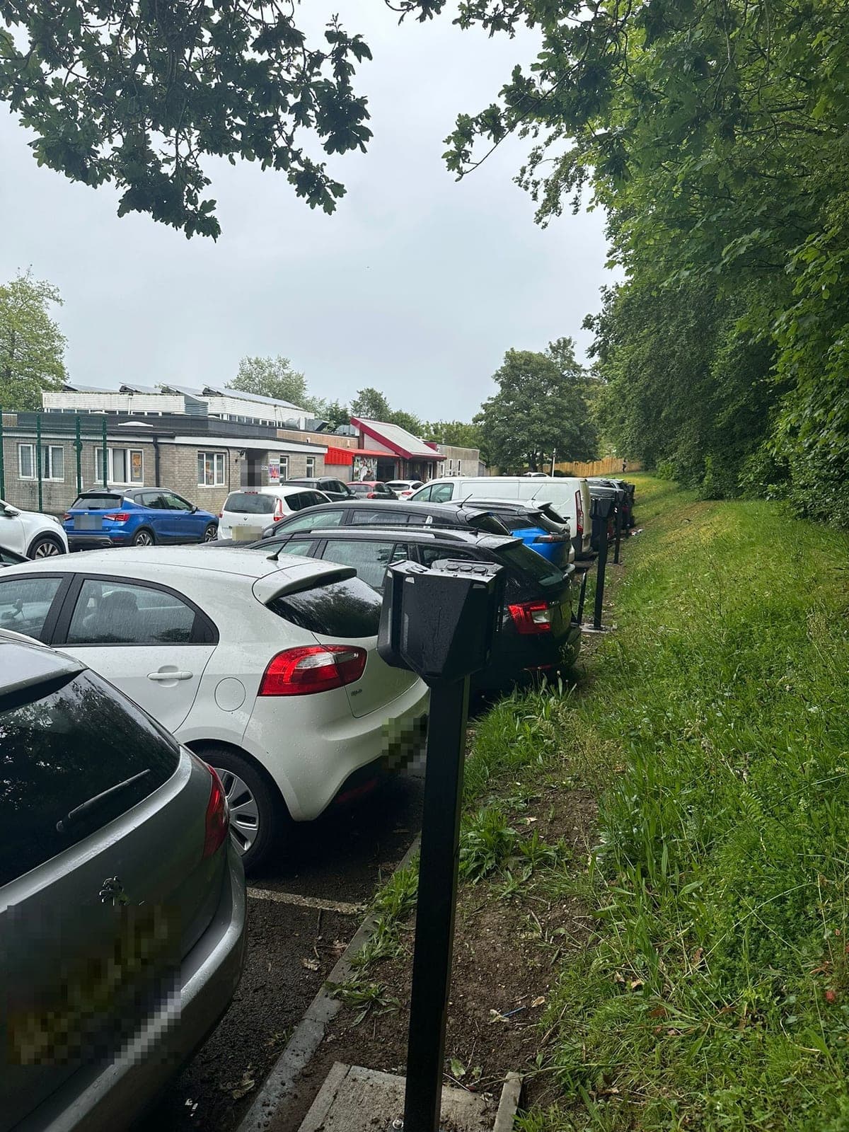 A row of EV chargers along the edge of a school car park